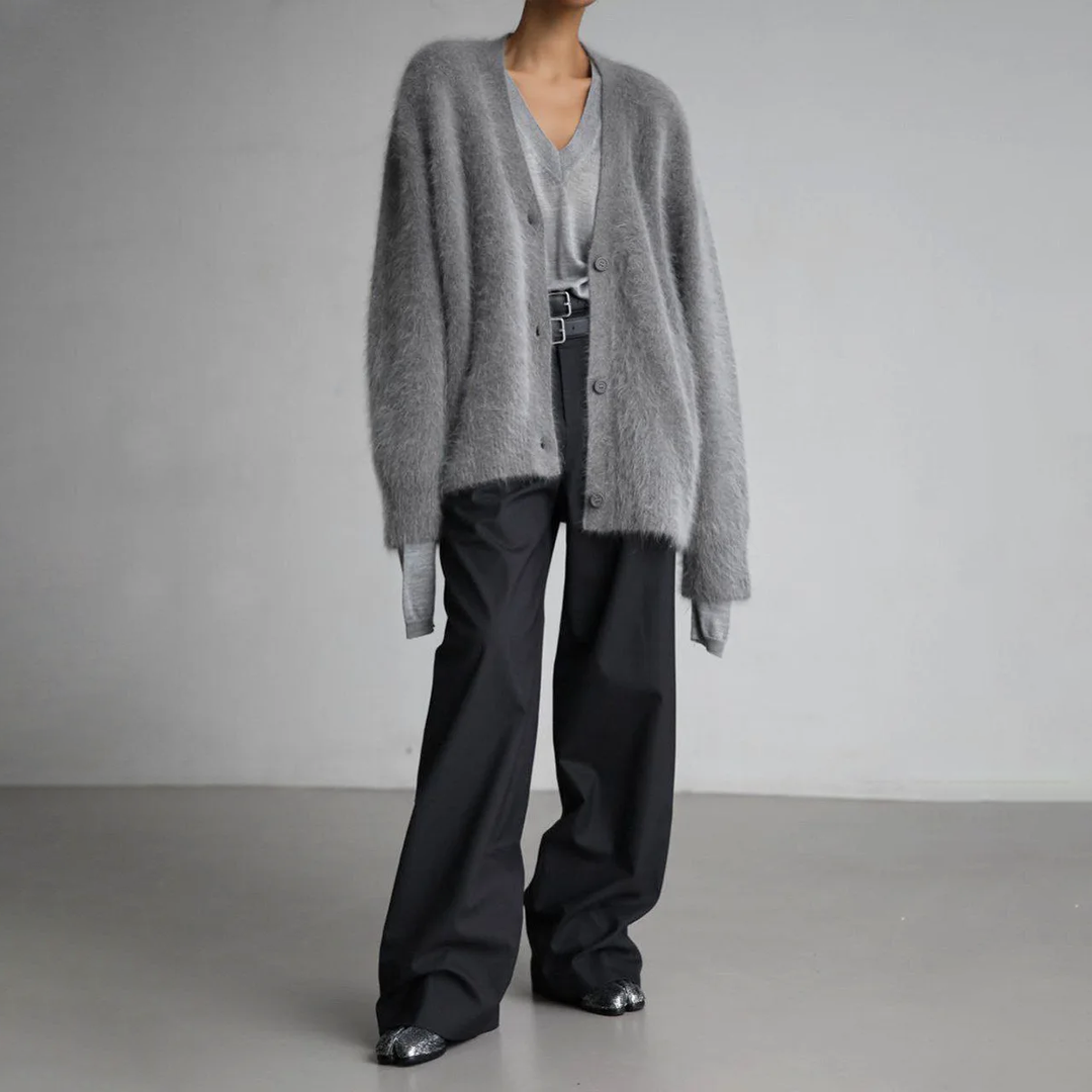 Graue flauschige Cardigan-Strickjacke kombiniert mit weiter schwarzer Stoffhose