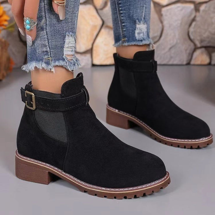 Nahaufnahme schwarzer Ankle Boots mit Zierschnalle und robuster Profilsohle