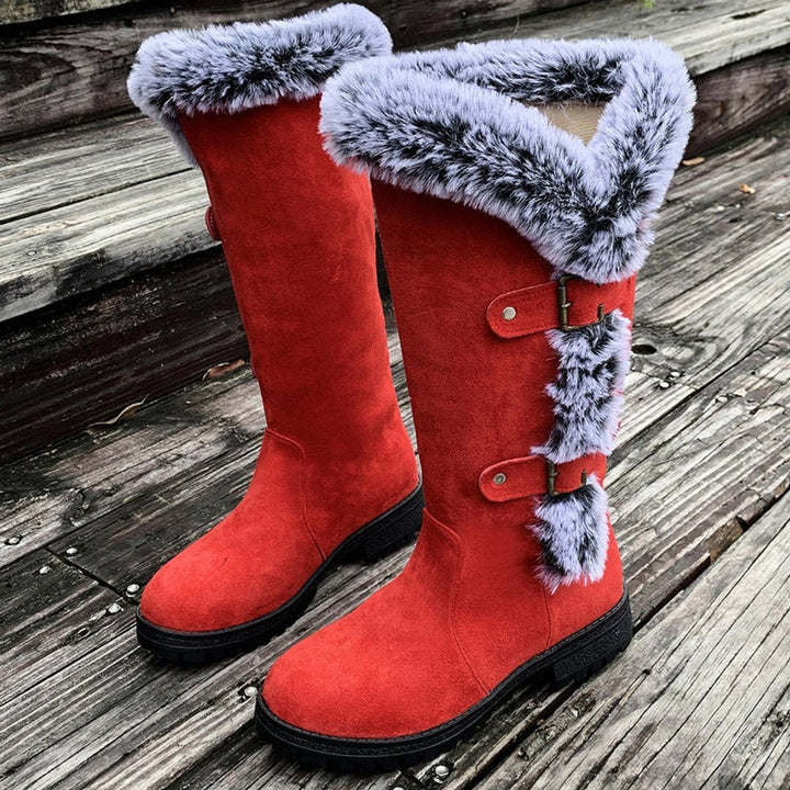 Cognacfarbene kniehohe Stiefel mit Fellbesatz auf Holzstufen drapiert