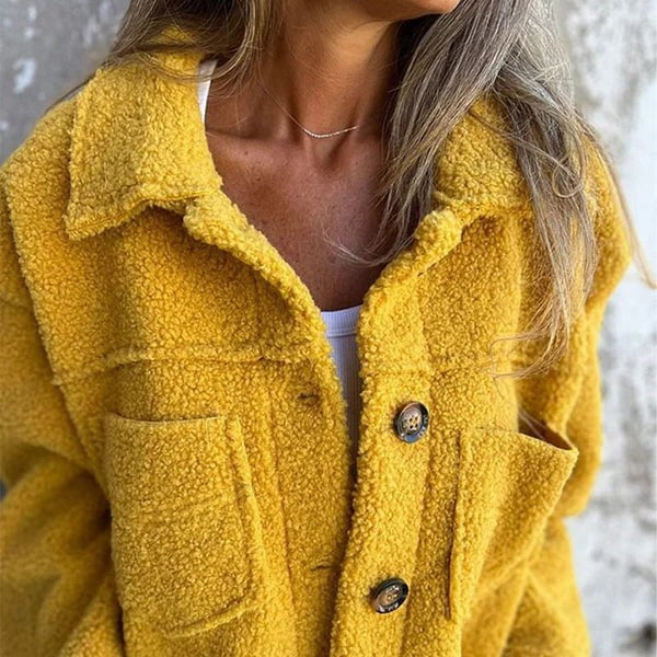 Nahaufnahme gelber Teddyjacke mit Knopfleiste und Revers am Ausschnitt