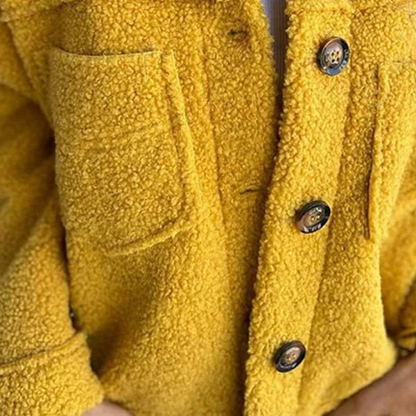 Detailansicht Knopfverschluss und Tasche einer gelben Fleecejacke aus Teddystoff