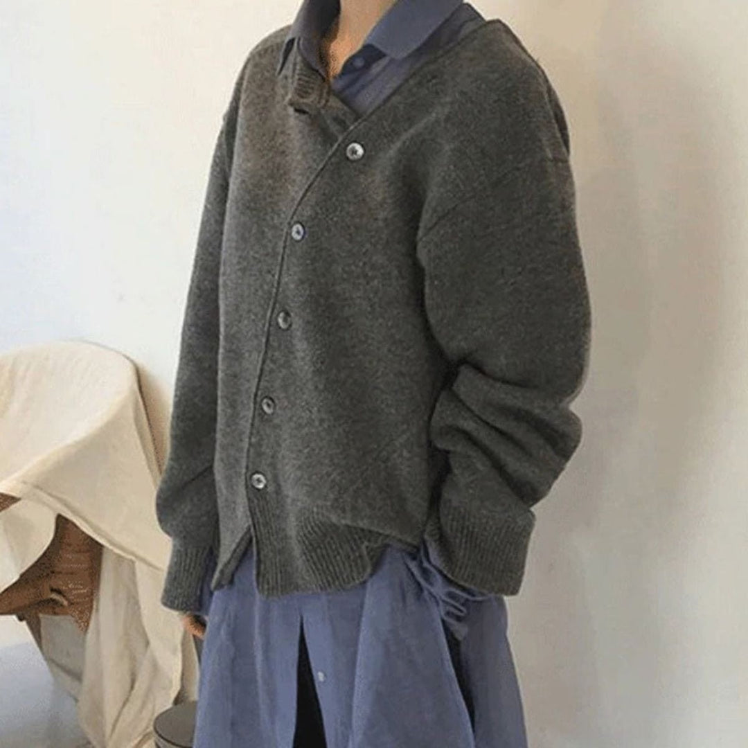 Graue oversized Strickjacke mit asymmetrischer Knopfleiste über Bluse getragen