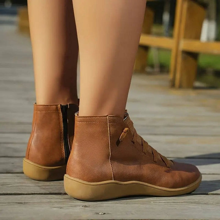 Cognacfarbene Stiefeletten mit Schnürung, Rückansicht auf Holzsteg