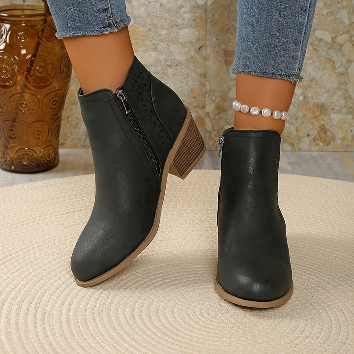 Braune Stiefelette mit Lochmuster und Blockabsatz, elegant am Bein getragen