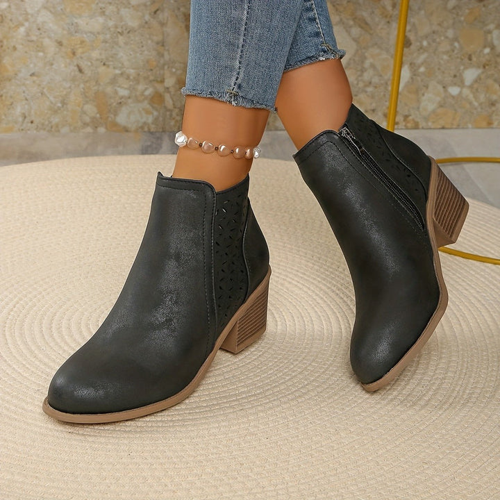 Blaue Stiefelette mit Lochmuster und Holzoptik-Blockabsatz in der Hand
