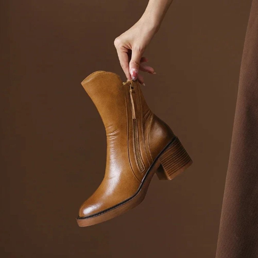 Cognacfarbene Lederstiefelette mit Blockabsatz freigestellt in der Hand gehalten