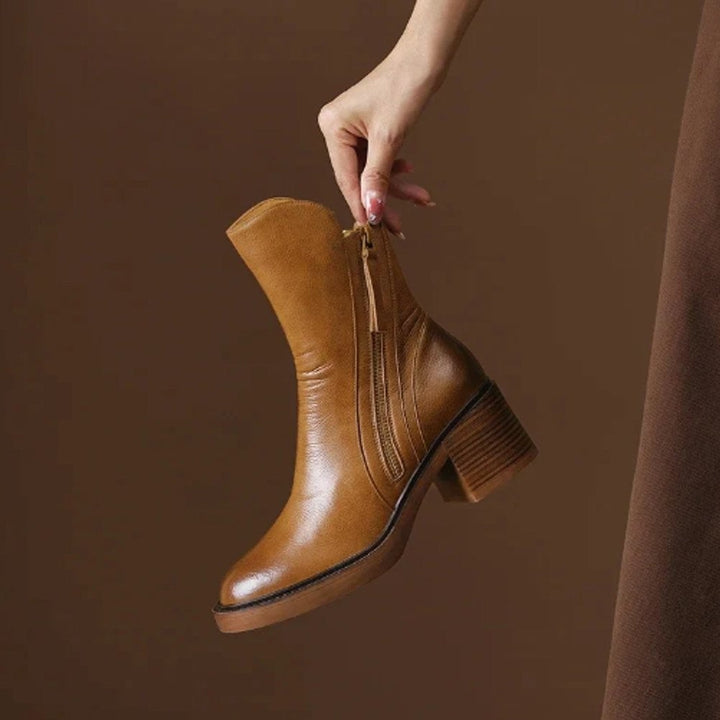 Cognacfarbene Lederstiefelette mit Blockabsatz freigestellt in der Hand gehalten