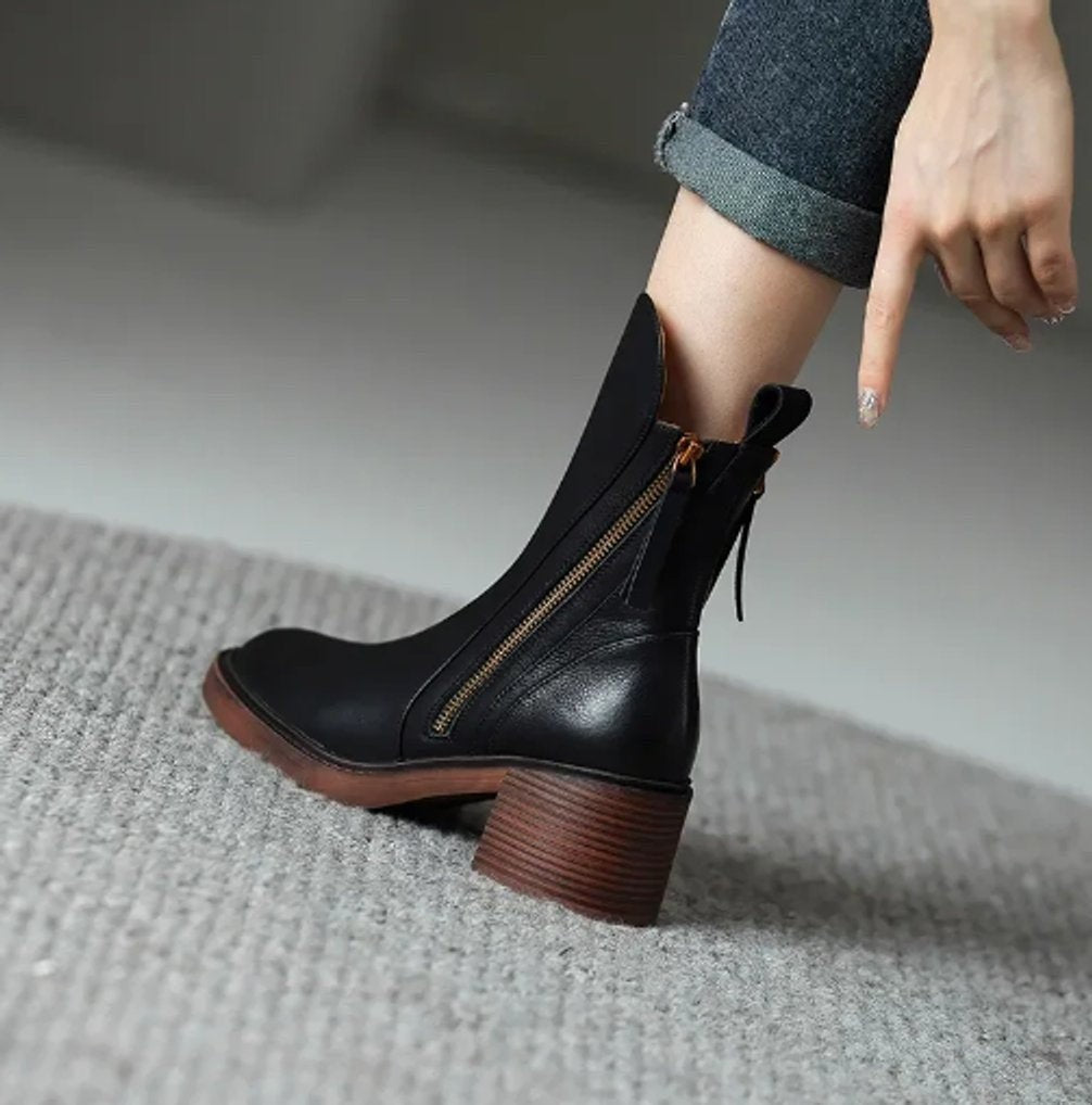 Schwarze Ankle Boots am Fuß getragen mit Blockabsatz und goldenem Reißverschluss
