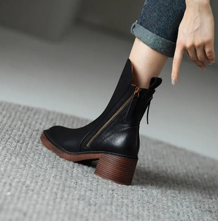 Schwarze Ankle Boots am Fuß getragen mit Blockabsatz und goldenem Reißverschluss