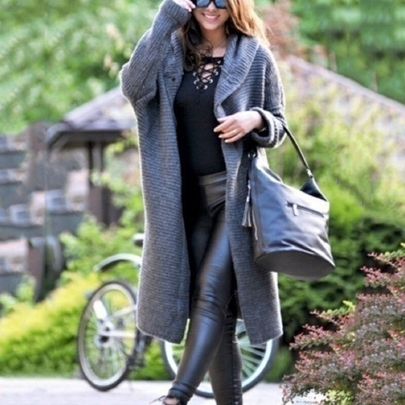 Grauer langer Strickmantel mit Kapuze, elegant kombiniert mit Handtasche