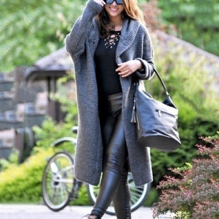 Grauer langer Strickmantel mit Kapuze, elegant kombiniert mit Handtasche