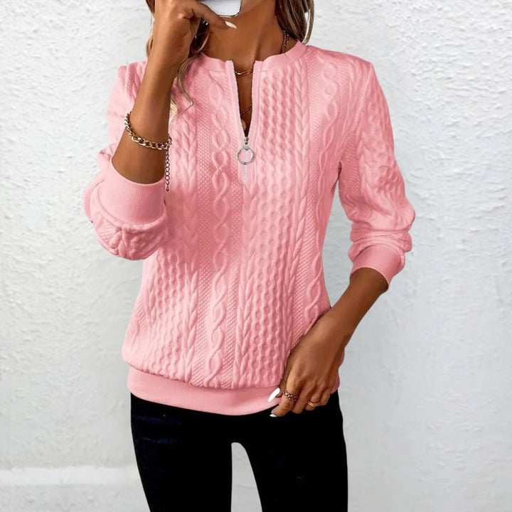 Rosa Strickpullover mit Zopfmuster und Reißverschluss-Ausschnitt vor weißer Wand