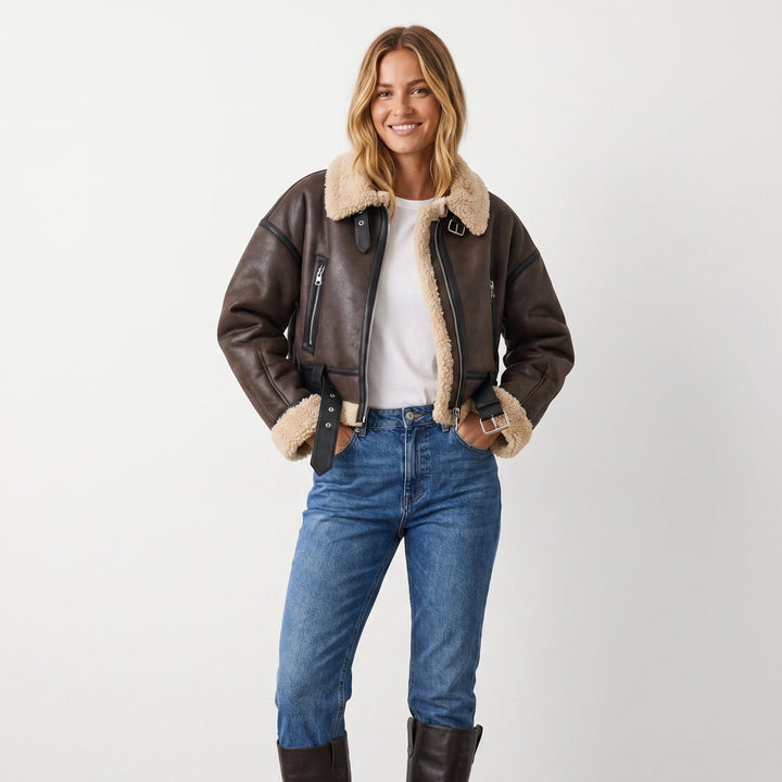 Lächelnde Frau in brauner Aviator-Bomberjacke kombiniert mit Jeans