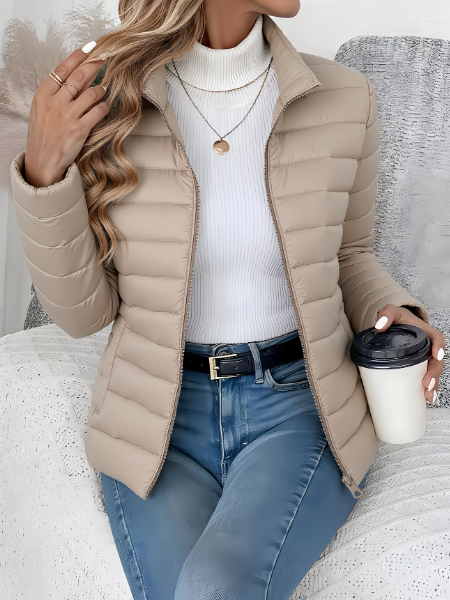 Beige Steppjacke mit Stehkragen, getragen mit Jeans und Kaffeebecher