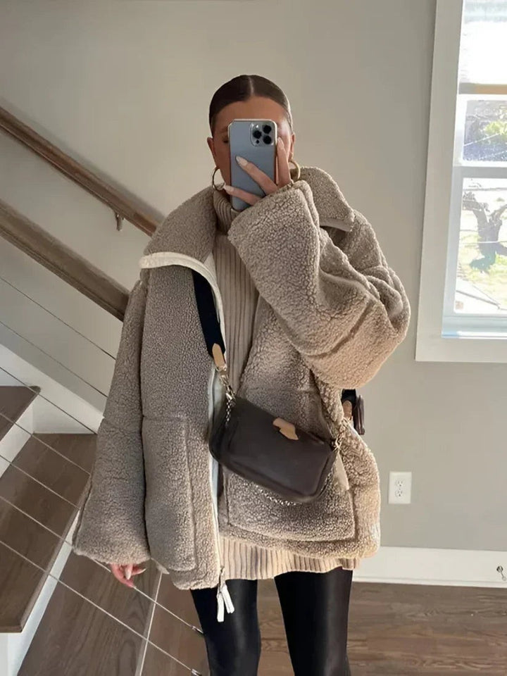 Model im Spiegel mit taupefarbener Oversized-Teddyjacke und schwarzer Umhängetasche