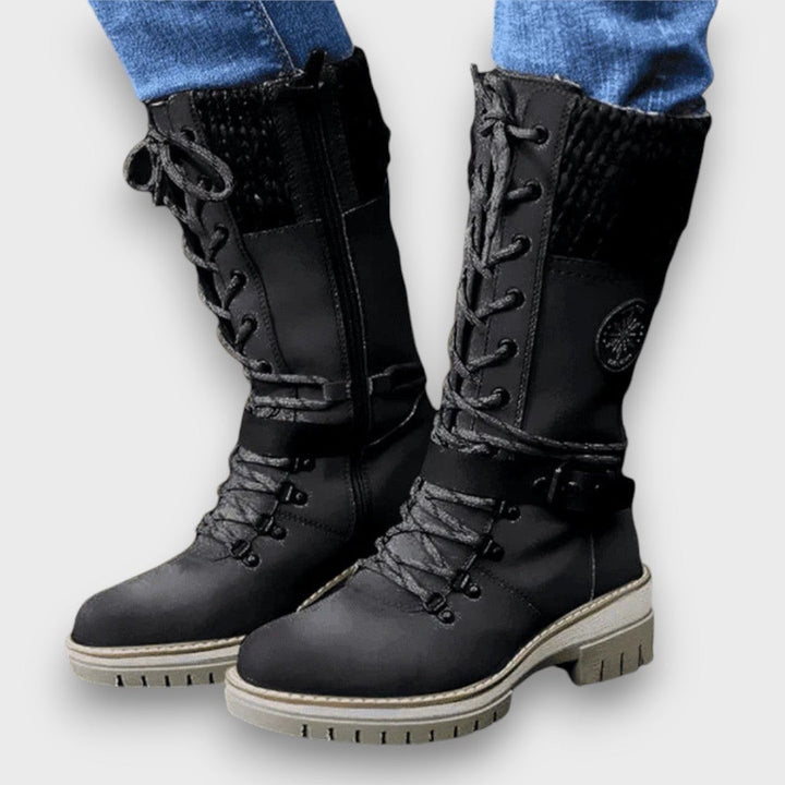 Schwarzer Winterstiefel mit Strickbesatz, Reißverschluss und Riemen am Bein getragen