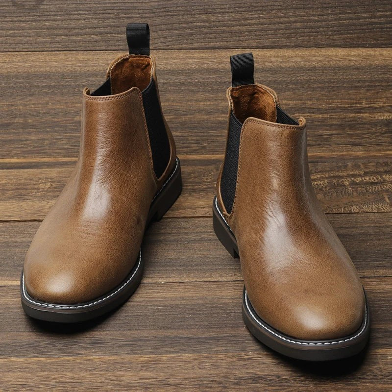Braune Chelsea Stiefeletten mit Kontrastnaht auf Holzboden präsentiert