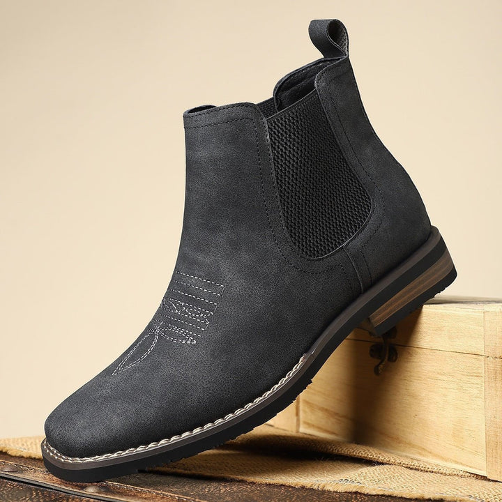 Anthrazitfarbene Chelsea Boots mit Wildleder-Optik auf Holzkiste