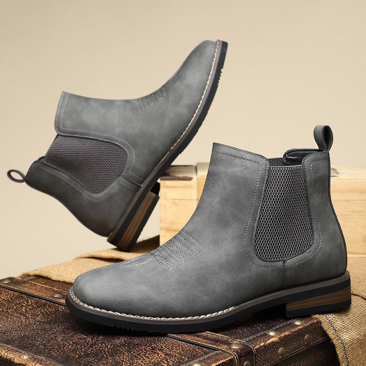 Taupefarbene Chelsea Stiefeletten mit rostbraunem Elastikeinsatz auf Vintage-Koffer