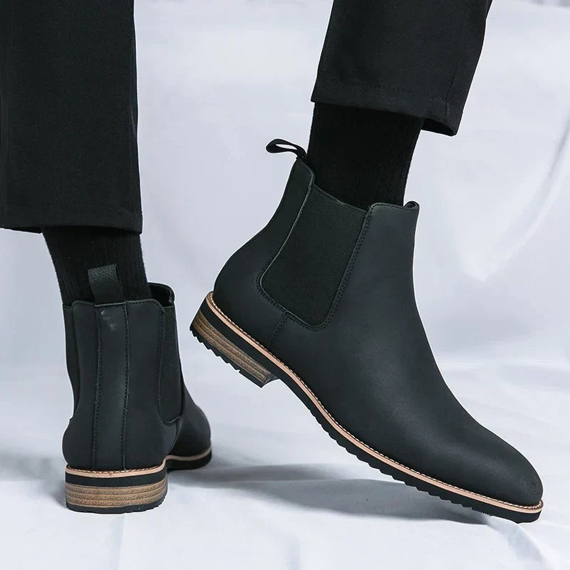 Schwarze Chelsea Boots aus veganem Leder, am Fuß getragen mit dunkler Anzughose