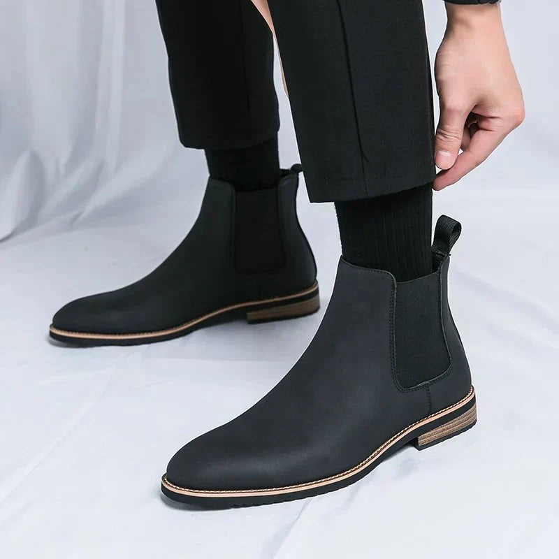 Schwarzer Chelsea Boot mit Zugschlaufe, seitliche Ansicht beim Anziehen