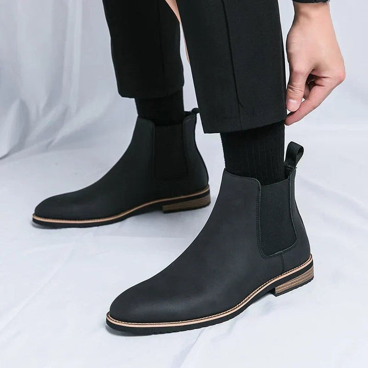 Schwarzer Chelsea Boot mit Zugschlaufe, seitliche Ansicht beim Anziehen