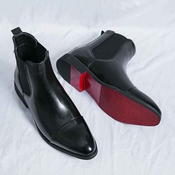 Paar schwarzer Chelsea Boots mit auffälliger roter Laufsohle