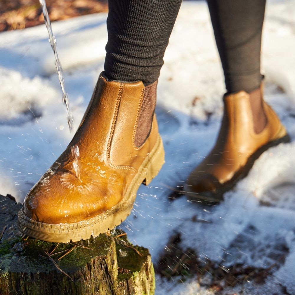 Wasserabweisende Chelsea-Stiefeletten in Camel beim Überqueren einer verschneiten Fläche