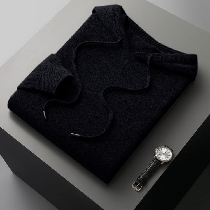 Schwarzer Strickhoodie mit Kapuze, gefaltet mit Kordelzug neben Armbanduhr