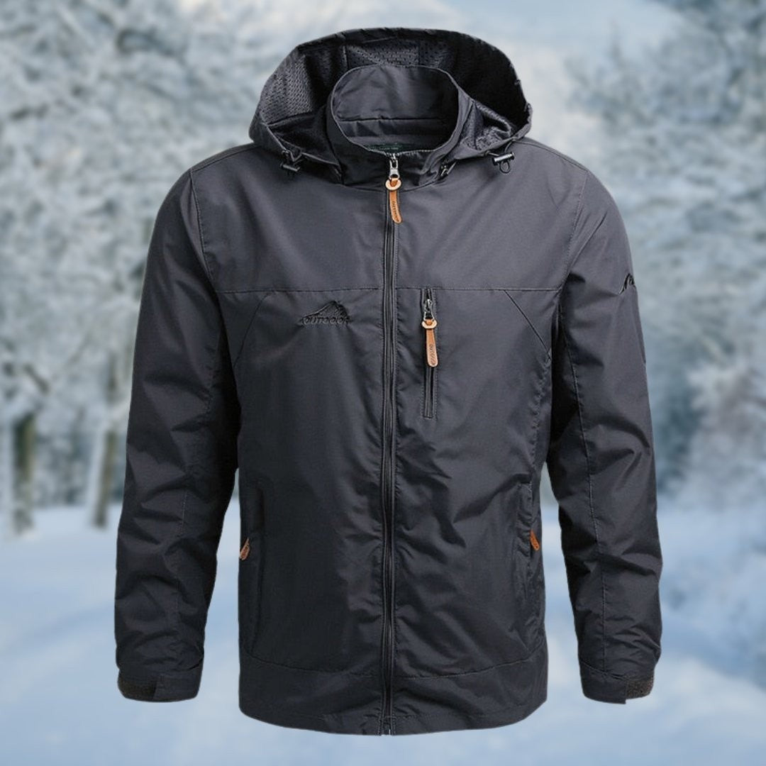 Anthrazitfarbene Herren-Funktionsjacke mit Kapuze vor Schneelandschaft