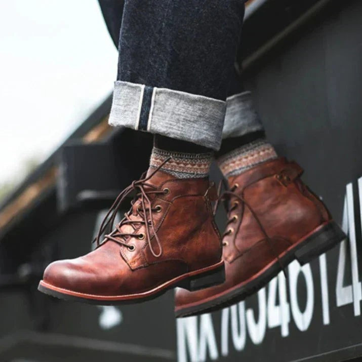 Braune Schnürstiefel im Used-Look an Herrenfüßen, hängende Beine