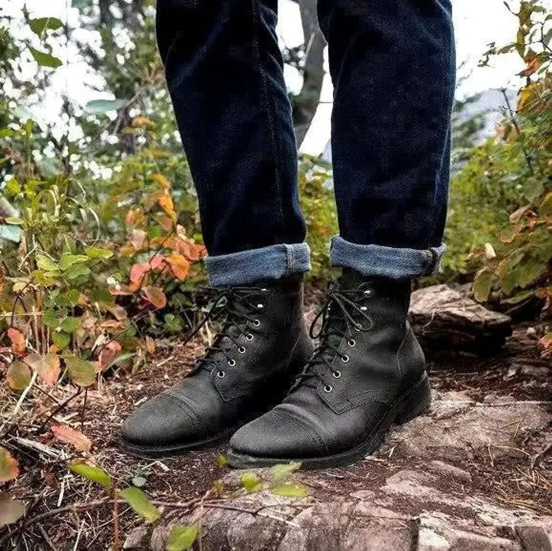 Schwarze Herren Stiefel mit Cap-Toe und Schnürung, getragen im Wald mit hochgekrempelter Jeans