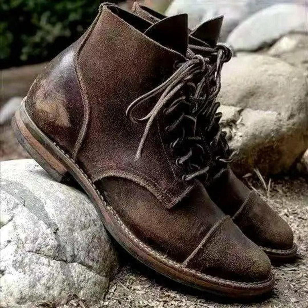 Braune Cap-Toe Stiefel aus veganem Leder mit robuster Gummisohle auf Steinen