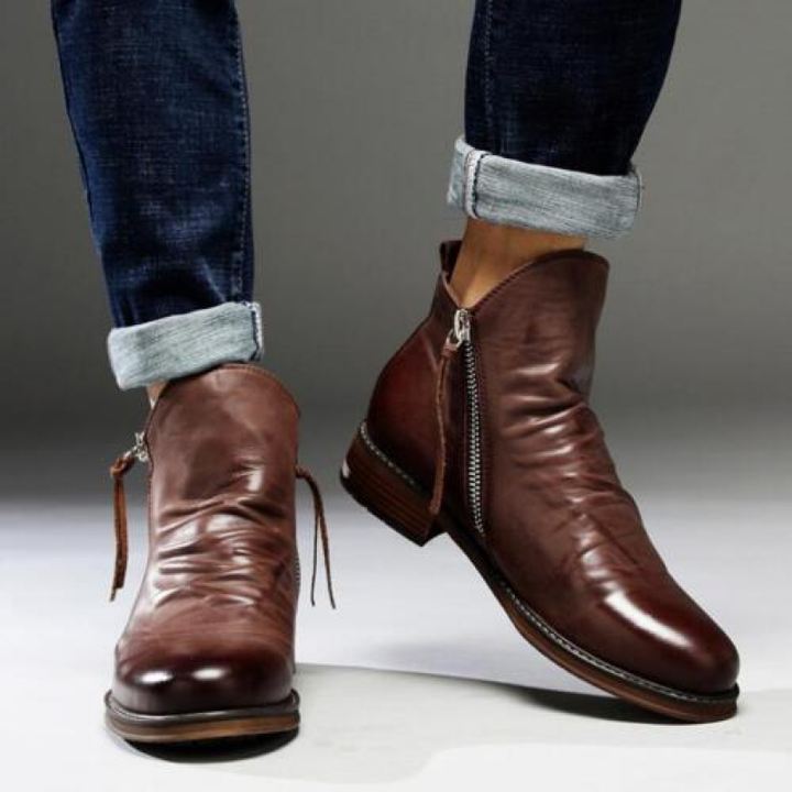 Braune Herren-Stiefelette mit gerafftem Schaft und seitlichem Reißverschluss zu Jeans getragen