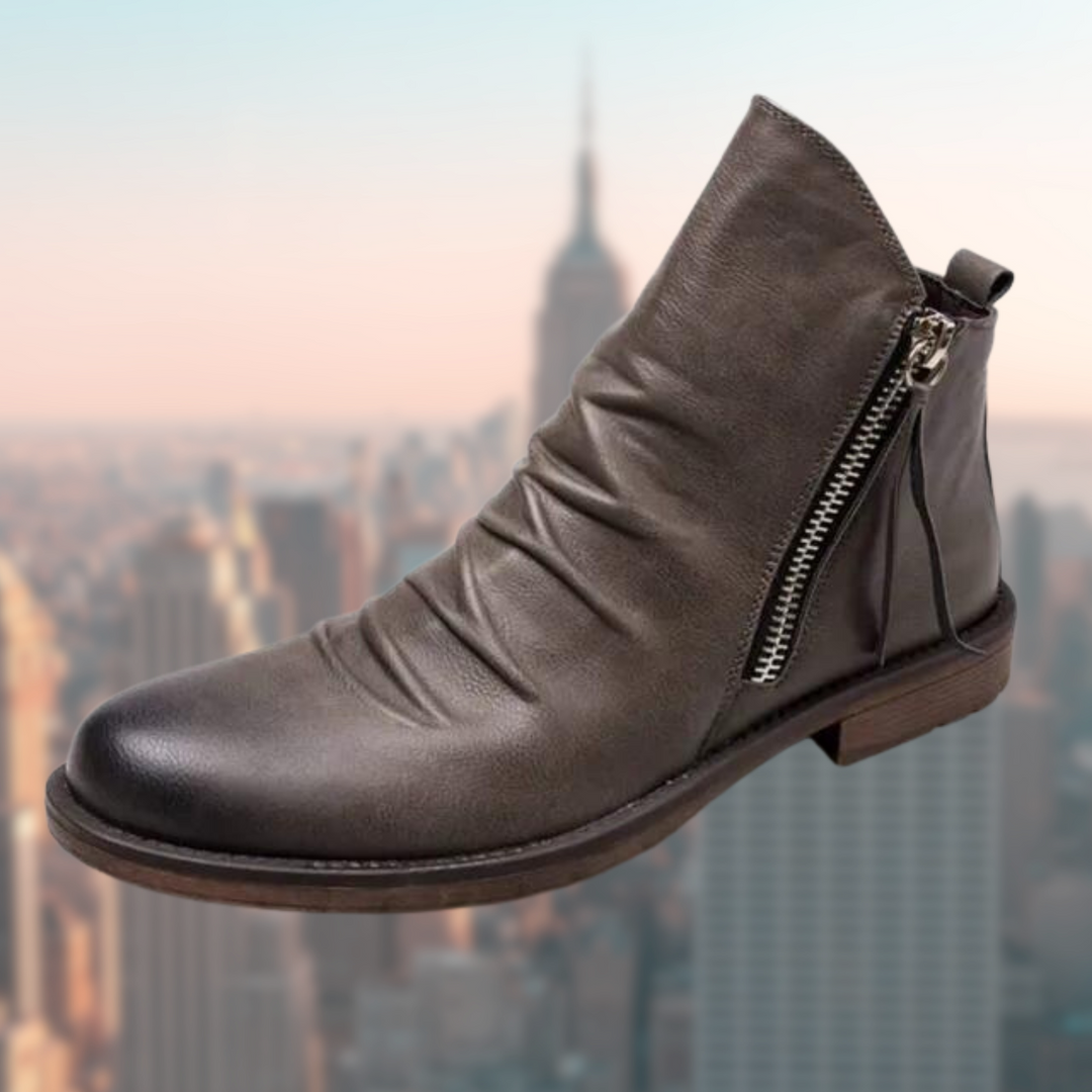 Graue Herren-Stiefelette mit gerafftem Schaft und silbernem Zipper freigestellt