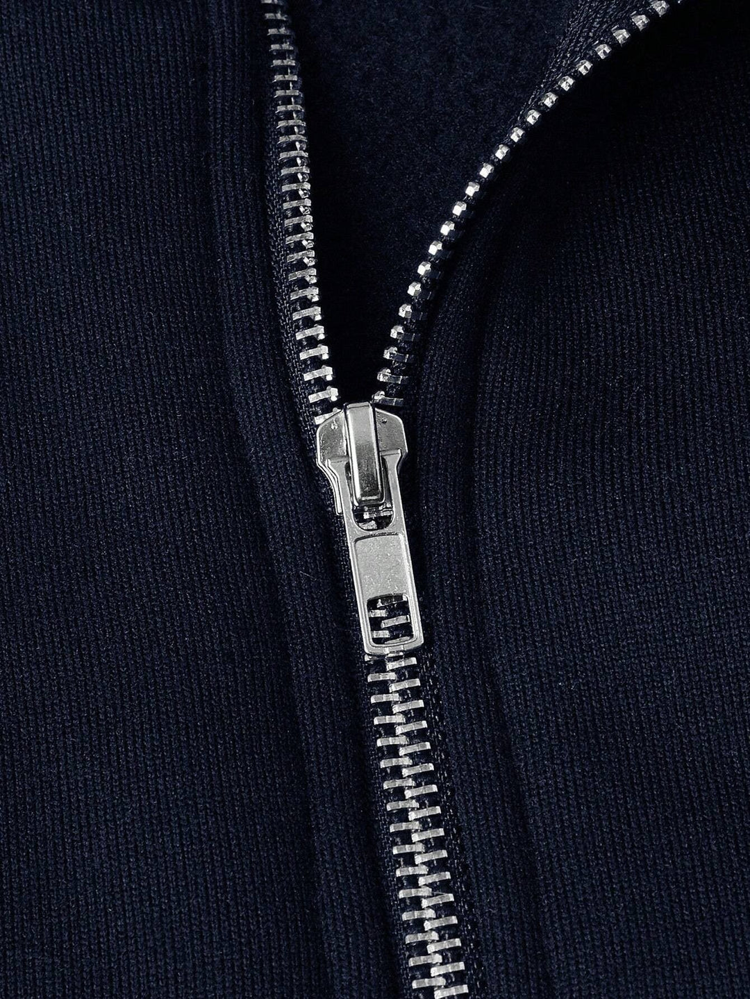 Nahaufnahme des silbernen Reißverschlusses am marineblauen Fleece-Pullover