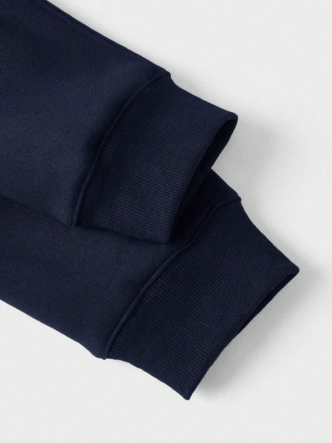 Detailansicht der gerippten Bündchen am marineblauen Herrenpullover