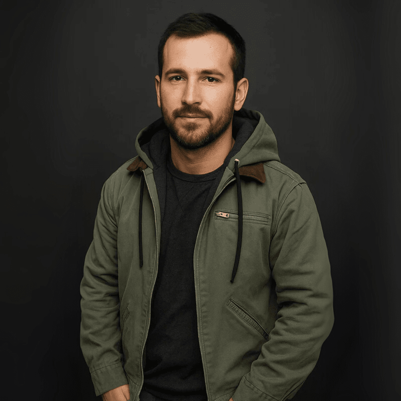Mann trägt olivgrüne Kapuzenjacke mit Cordkragen vor dunklem Hintergrund