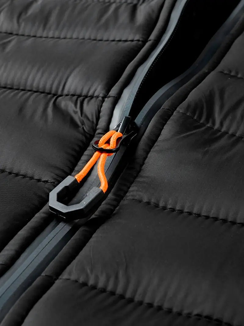 Nahaufnahme des Reißverschlusses mit orangefarbenem Zugband an Steppjacke