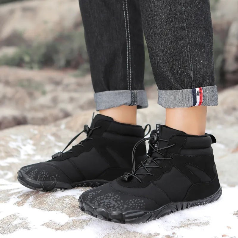 Schwarze Winterstiefel mit Zugkordel und Profilsohle beim Wandern auf Felsen getragen