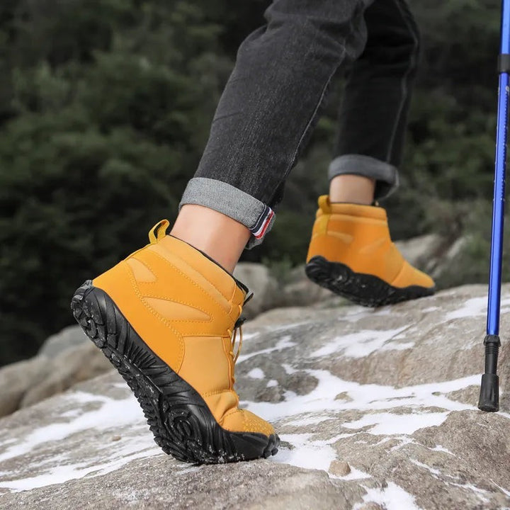 Senffarbene Winterstiefel mit Profilsohle beim Wandern mit Trekkingstock im Schnee