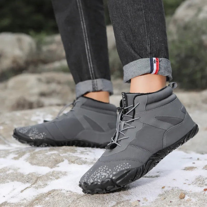 Graue gefütterte Winterstiefel mit Zugkordel beim Gehen auf verschneitem Stein