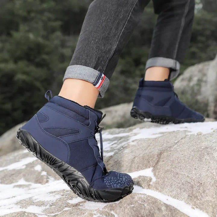 Dunkelblauer Winterstiefel mit rutschfester Sohle beim Klettern über Steine